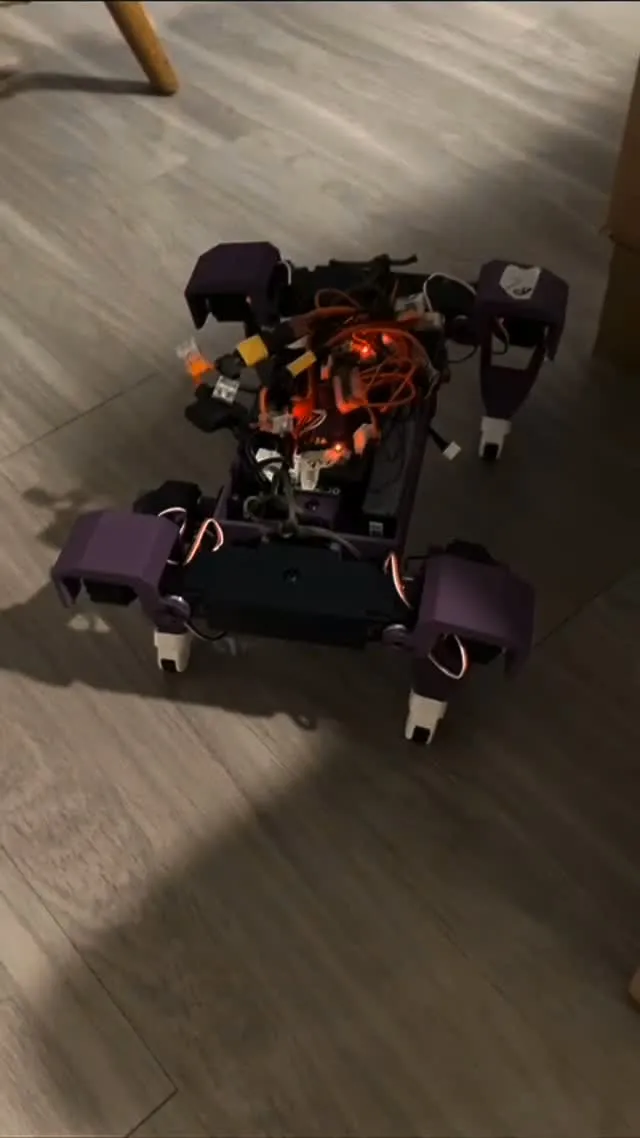 Top-down frame of Dog V4 walking with its printed legs and electronics exposed
